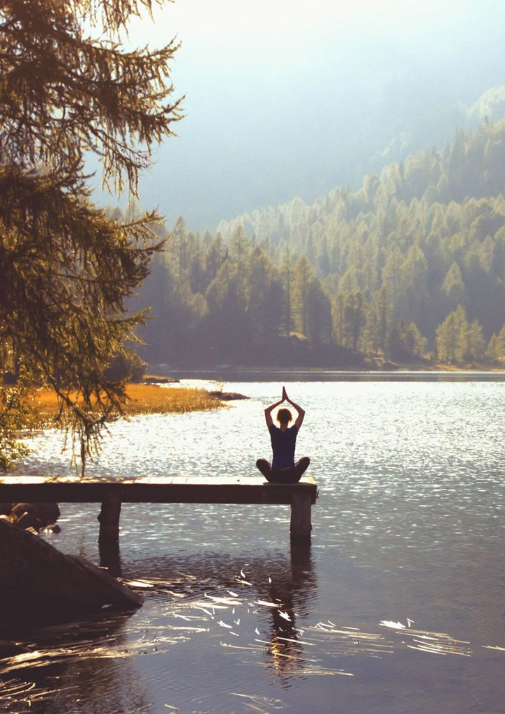 Woman Sitting In Yoga Pose On Dock
